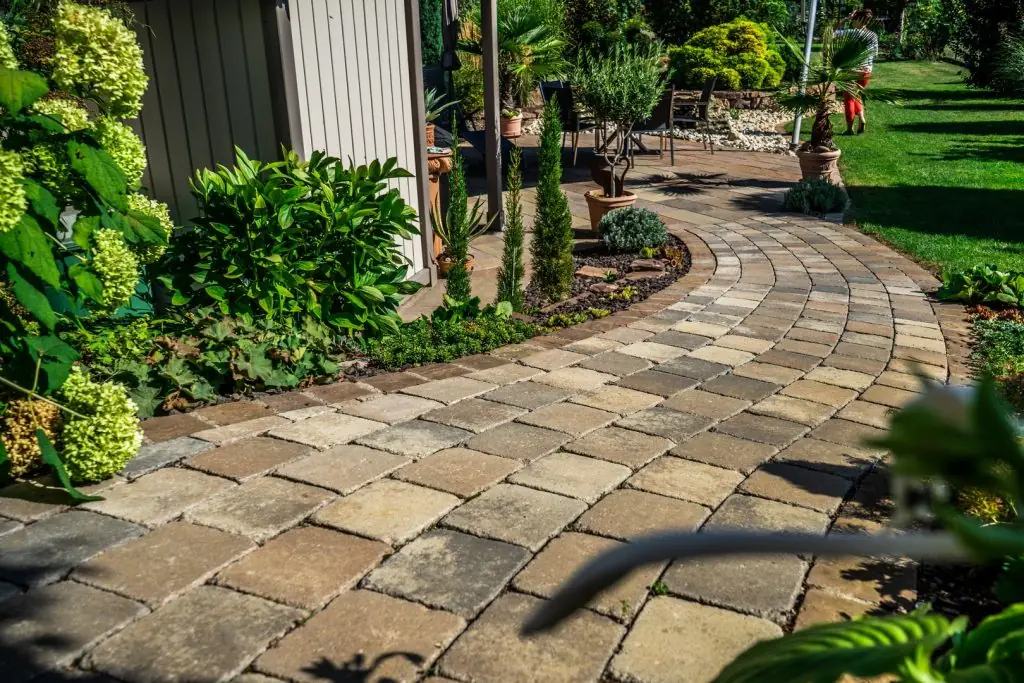 Geschwungener Naturstein-Pflasterweg durch bepflanzten Garten