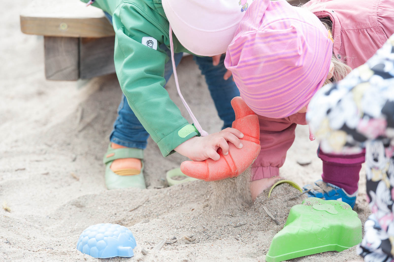 Mehrere Kinder spielen gemeinsam im Sandkasten mit bunten Sandförmchen