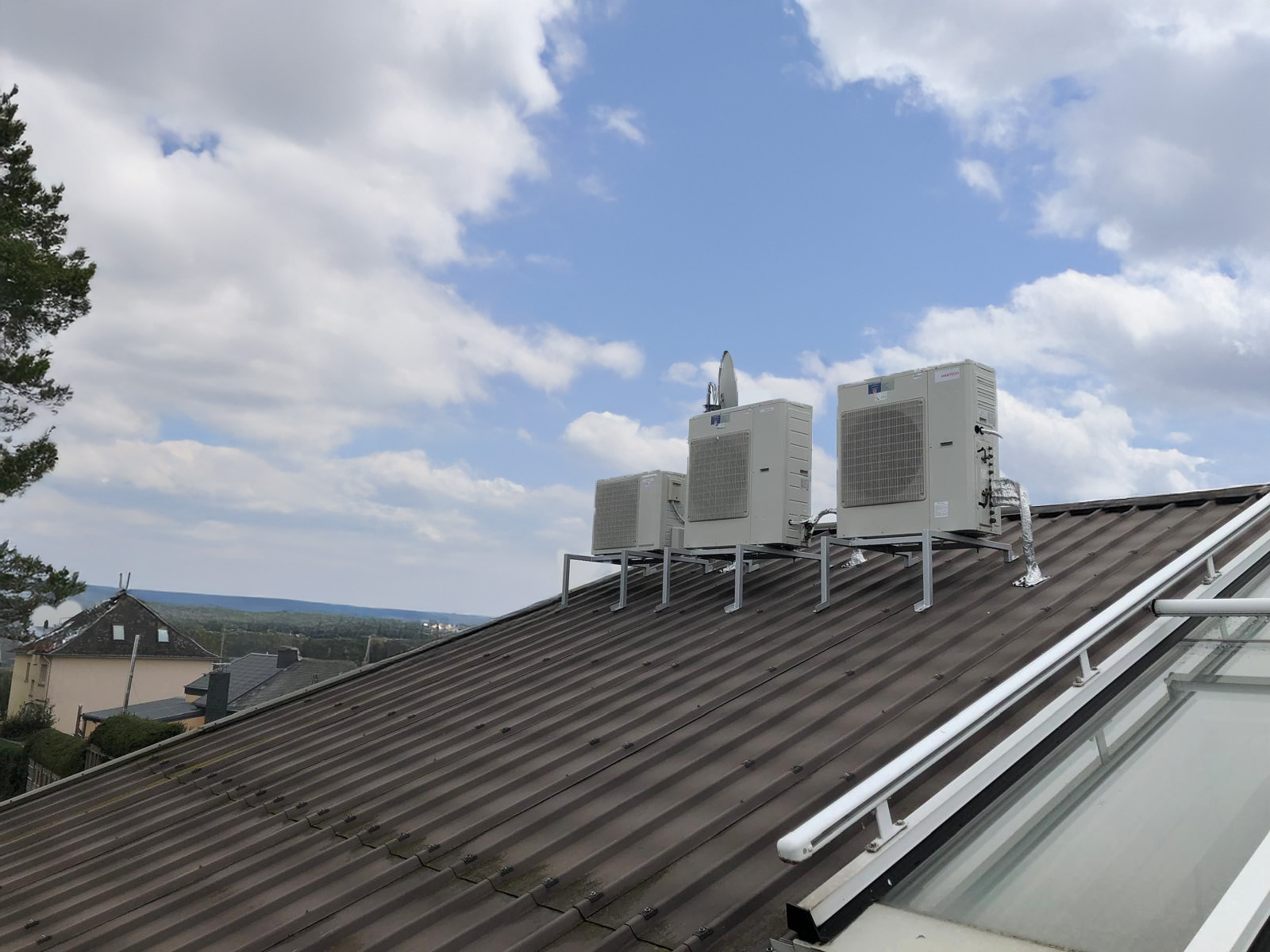 Mehrere Daikin Klimaanlagen-Außengeräte auf einem Gestell auf einem Schrägdach über Karlsruhe