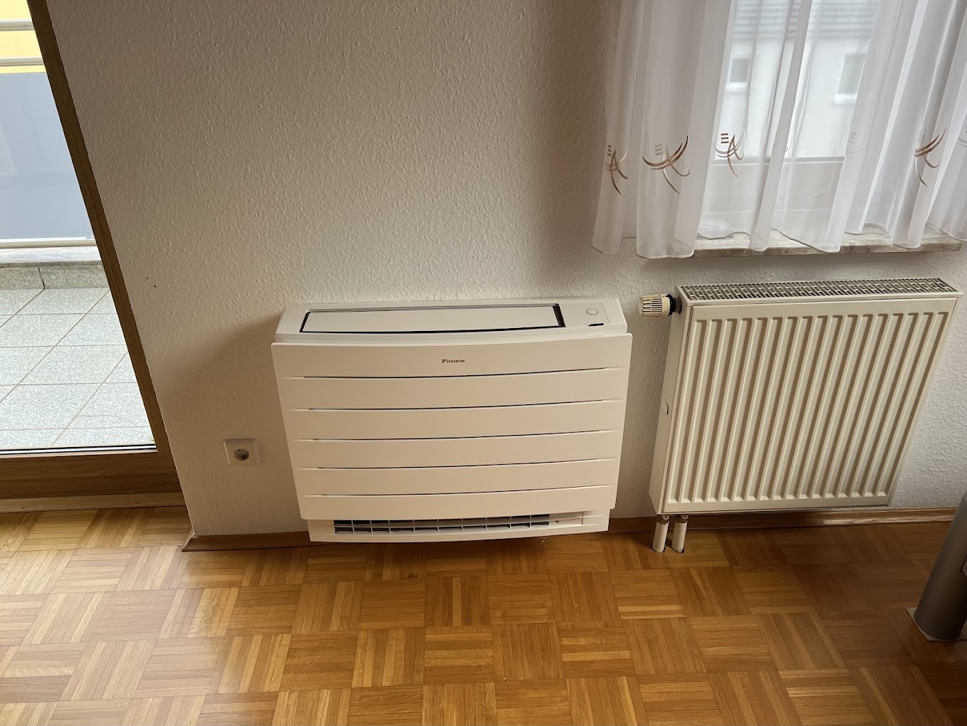 Daikin Konsolengerät bodennah an der Wand in einem Wohnzimmer neben dem Heizkörper